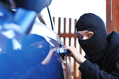 Young man in mask trying to steal a car
